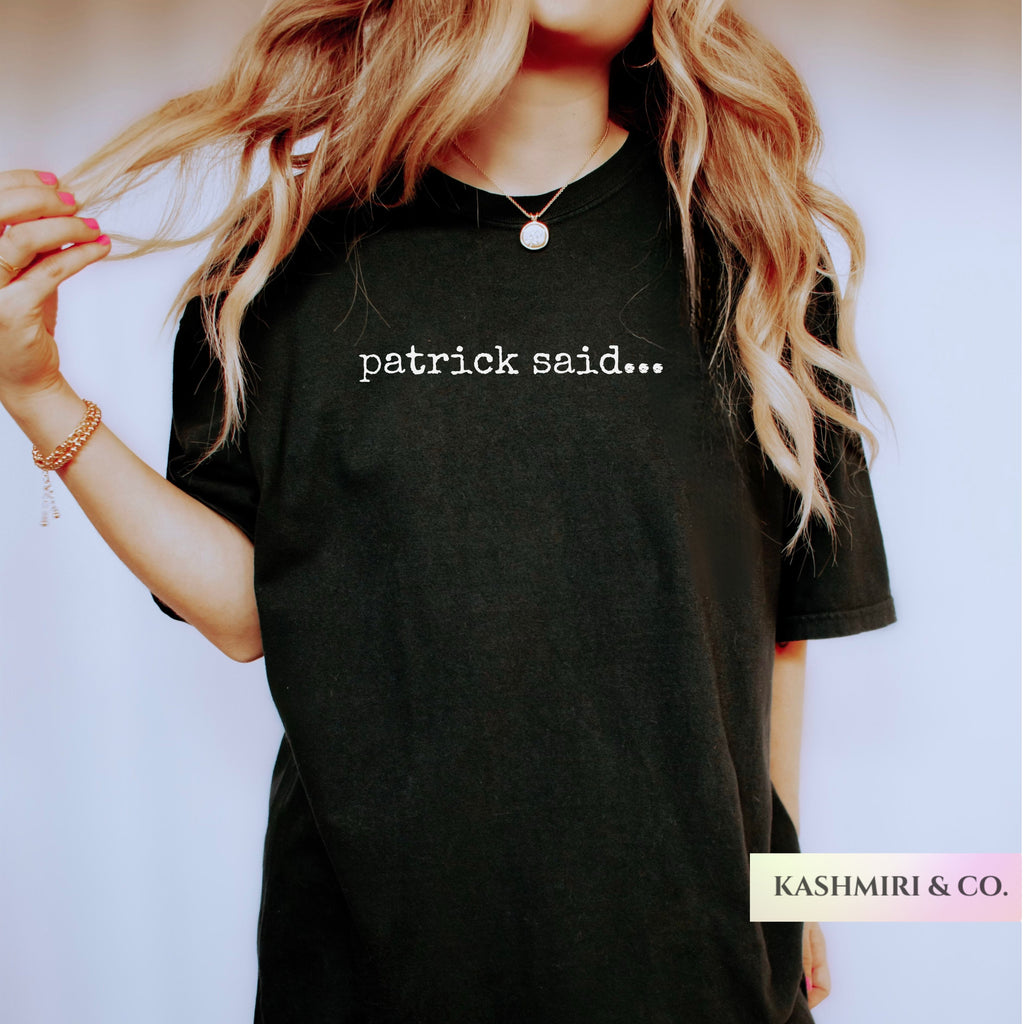 A woman wearing a black oversized T-shirt with the white text 'patrick said.