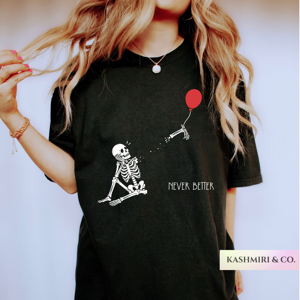 A woman wearing a black graphic t-shirt with a white skeleton holding a red balloon and the text 'NEVER, BETTER'.