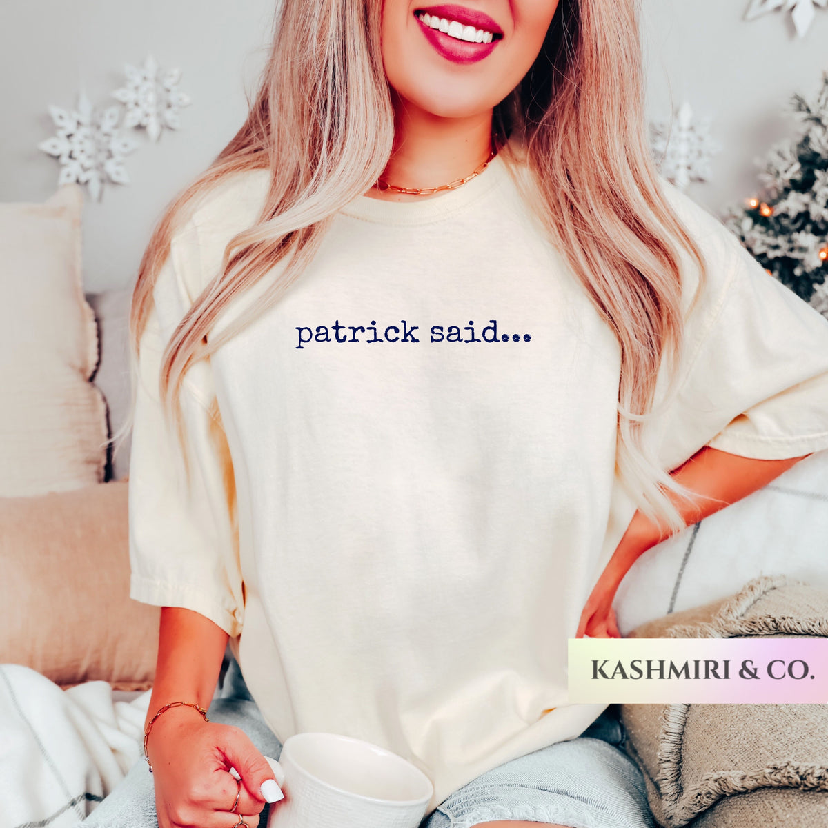 A woman wearing an oversized cream-colored t-shirt with the text 'patrick said.