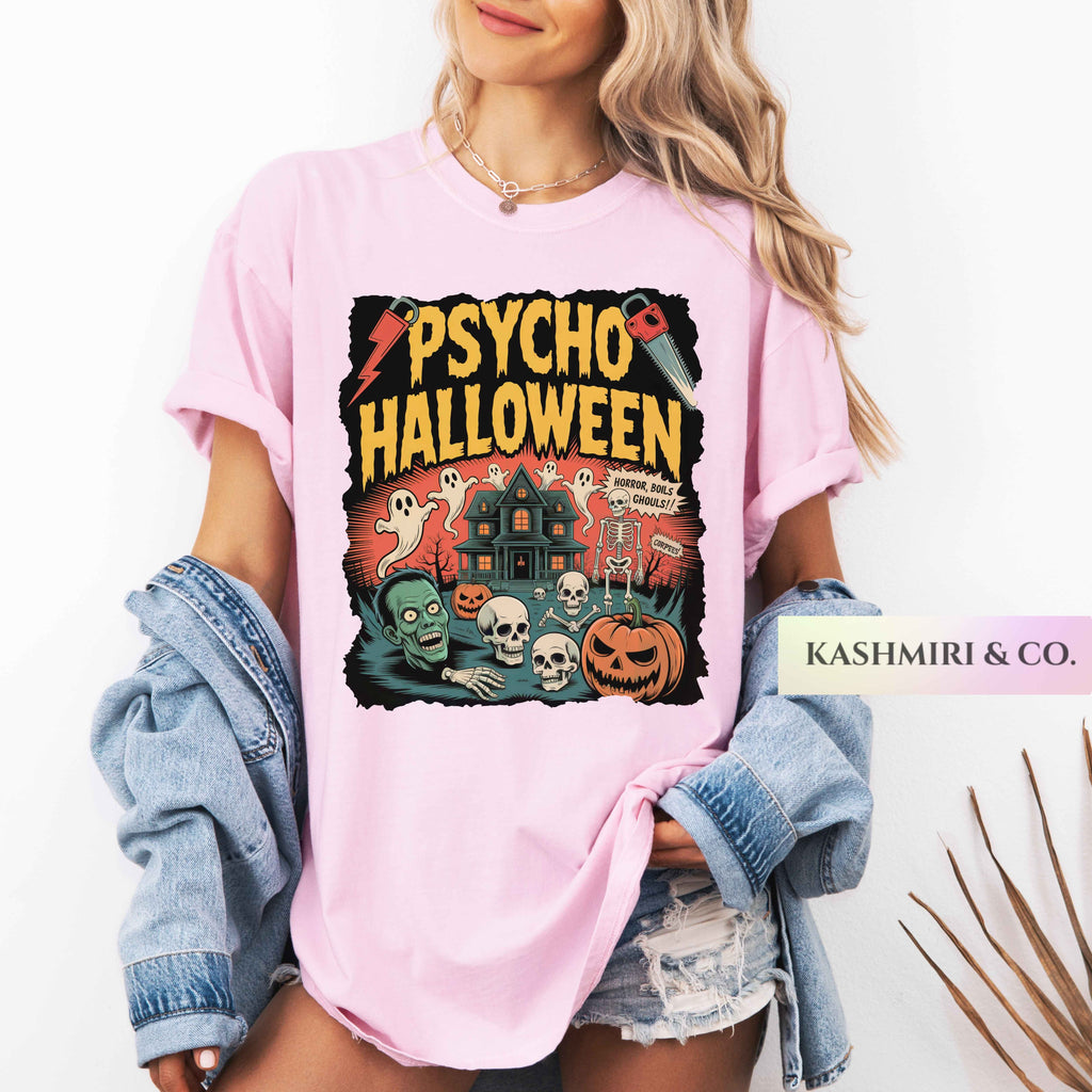 A woman wearing a light pink graphic T-shirt with a 'Psycho Halloween' print, styled with an open blue denim jacket and distressed denim shorts. The brand name 'KASHMIRI & CO.