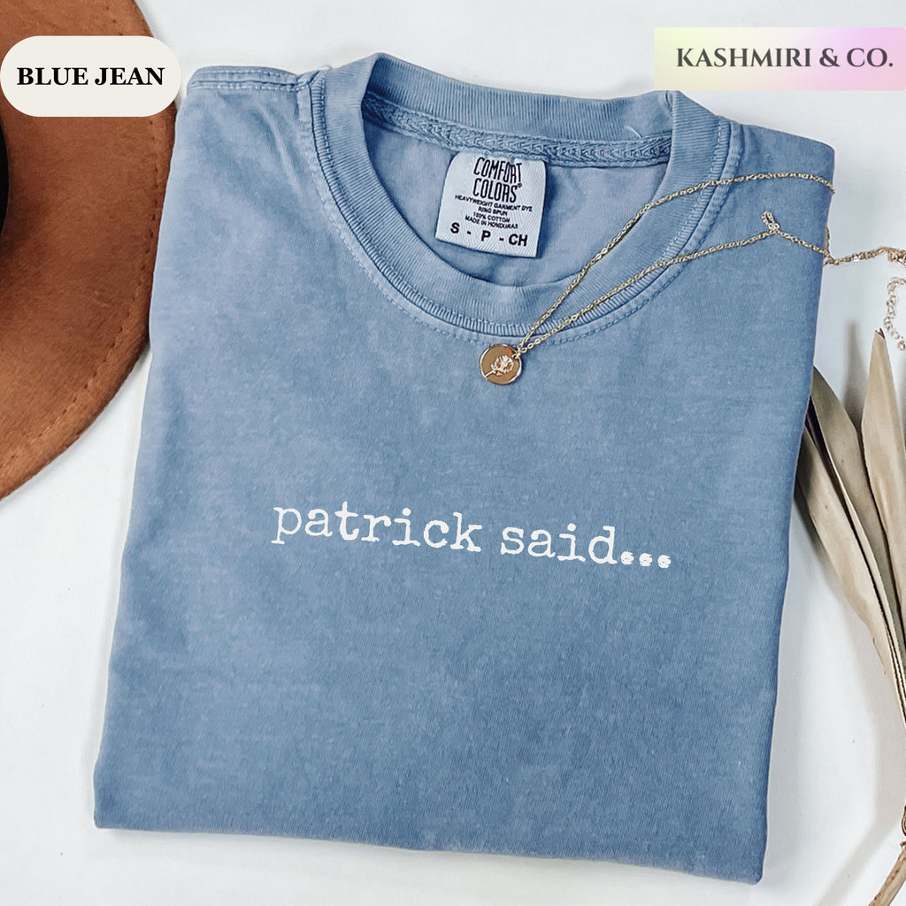 A folded light blue washed T-shirt with the phrase 'patrick said.